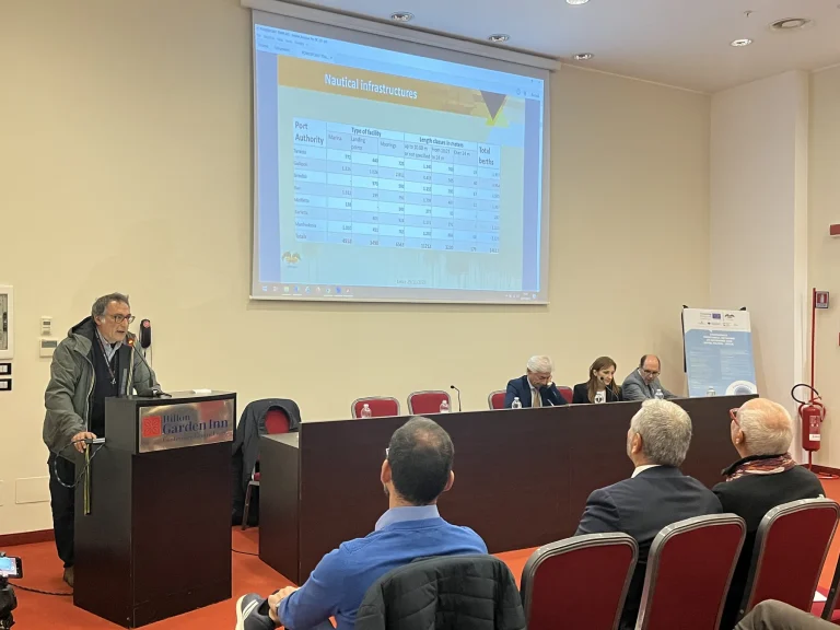 Un intervento dal leggio davanti alla platea della conferenza — PORTOLANES, Hotel Hilton Garden Inn, Lecce